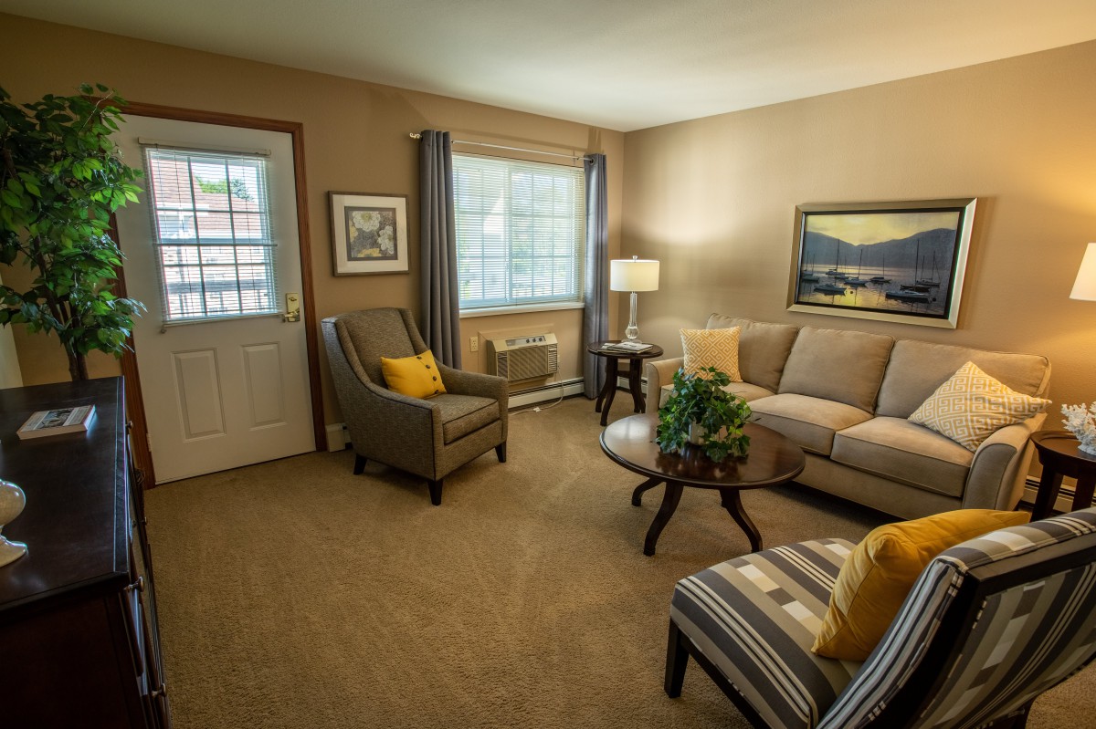 A cozy living room interior with a sofa, armchairs, and a coffee table arranged neatly.