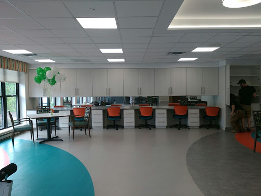 A modern office workspace featuring multiple desks and ergonomic chairs in a bright, open environment.