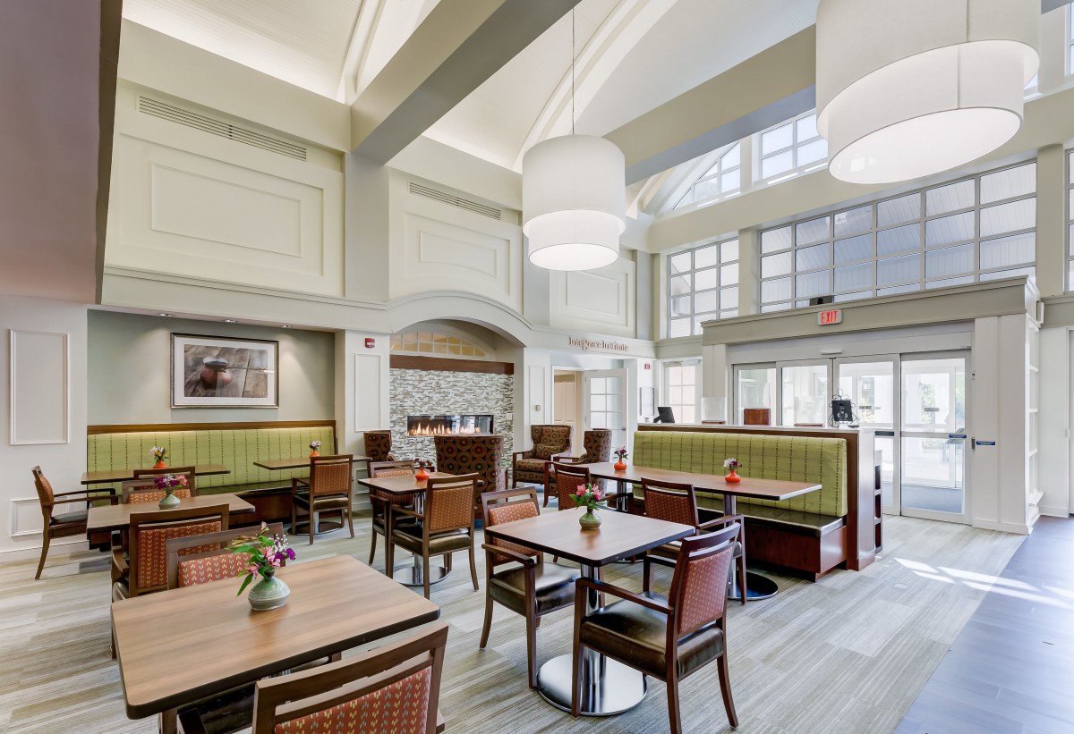 A modern restaurant interior featuring elegant tables, comfortable seating, and large windows for natural lighting.