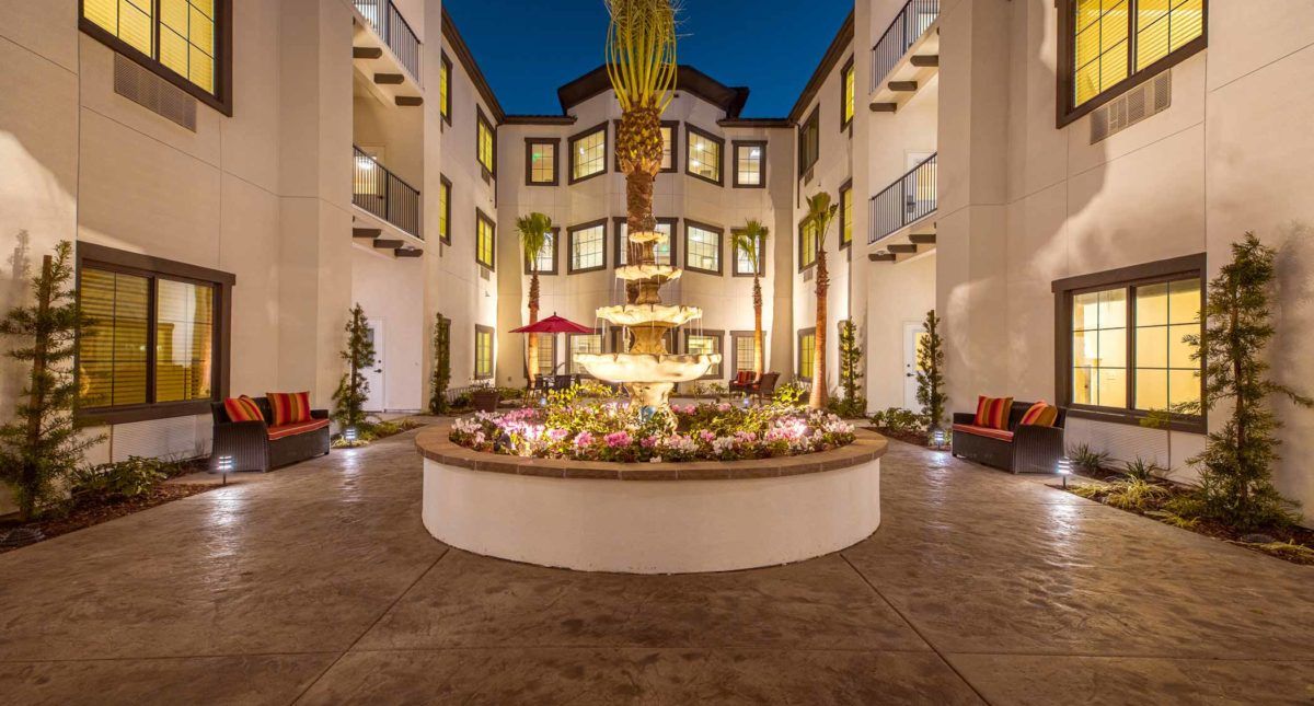 A beautifully lit courtyard featuring a central fountain at night.