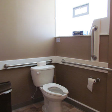 An accessible bathroom featuring a toilet with grab bars and handrails for safety.