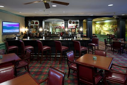 A cosy bar and restaurant interior with red leather seating and wooden tables.