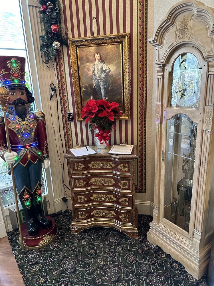 A vintage-themed interior with an ornate cabinet, festive poinsettia, and a decorative soldier figurine beside a framed painting.