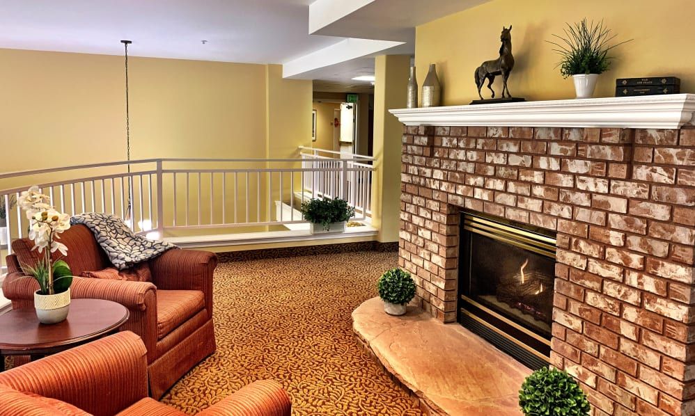 A cozy living room featuring a brick fireplace, plush armchairs, and warm lighting.