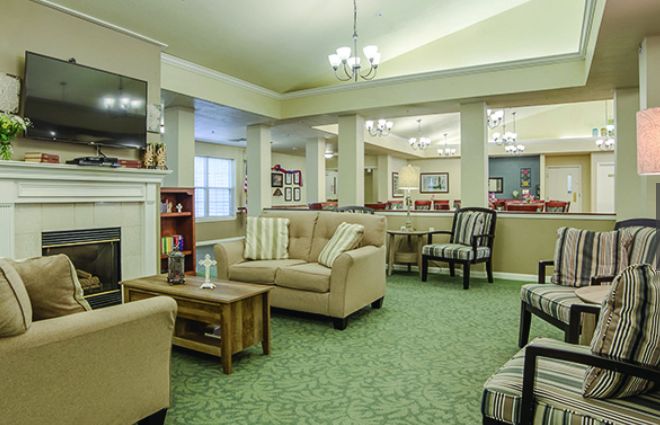 A cozy living room with comfortable sofas, a coffee table, and a television, featuring elegant chandeliers and soft carpeting.