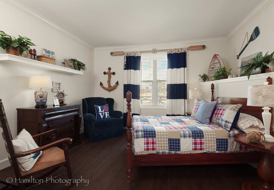 A nautical-themed bedroom featuring anchor decor and a checkered quilt on the bed.