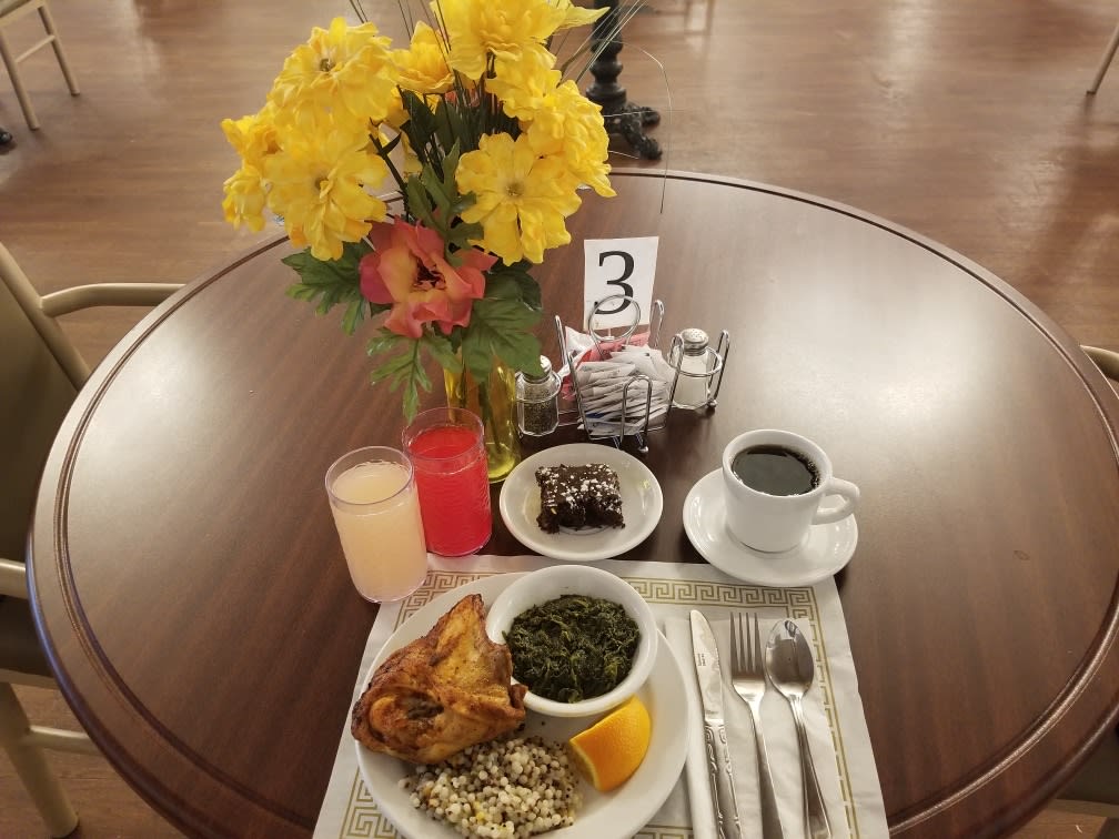 A neatly arranged breakfast table with a colorful flower vase and various dishes.