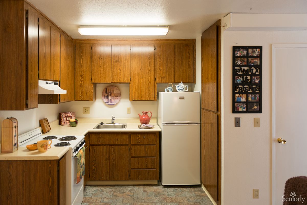 A cozy kitchen with wood cabinets, a refrigerator, sink, and stove.