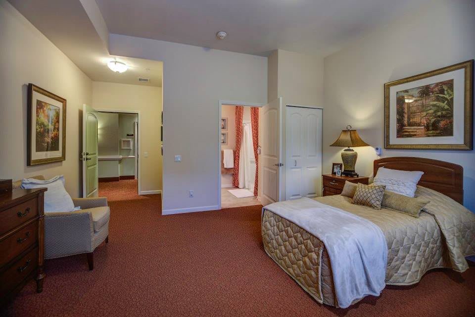 A well-furnished hotel room with a bed, nightstand, and seating area.