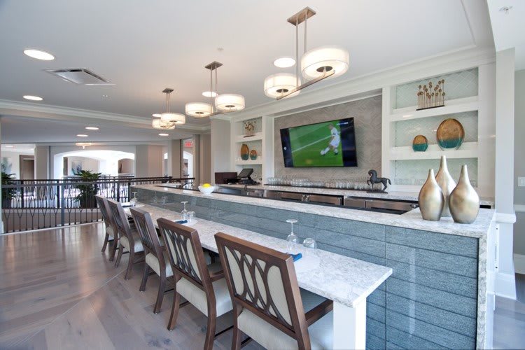 A modern indoor bar with stylish seating and a television on the wall.