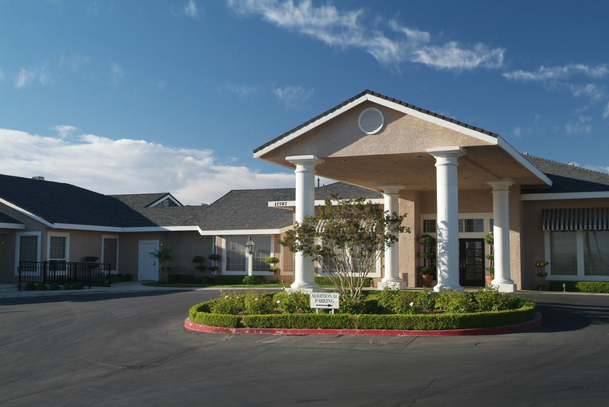 A modern residential building entrance with columns and landscaped surroundings.