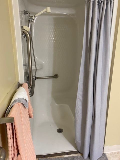 A bathroom with a shower, featuring a curtain and towels.