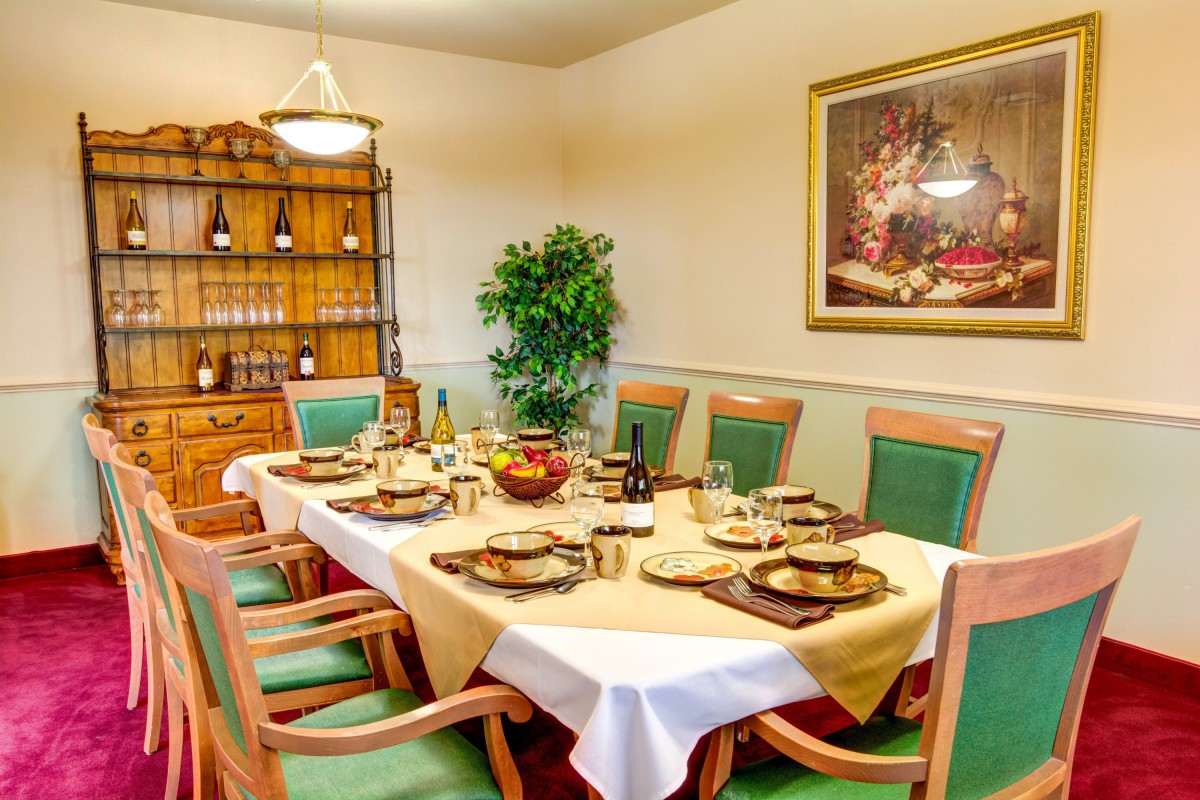 Elegantly set dining room table with green chairs and artful decor.