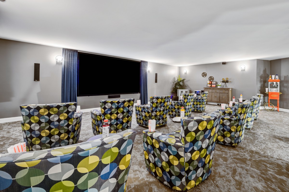 A modern home theater room with colorful patterned chairs and a large projector screen.