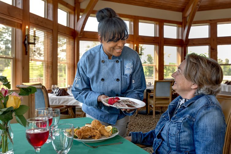 A chef serving food to a customer in a restaurant setting, showcasing hospitality and service.