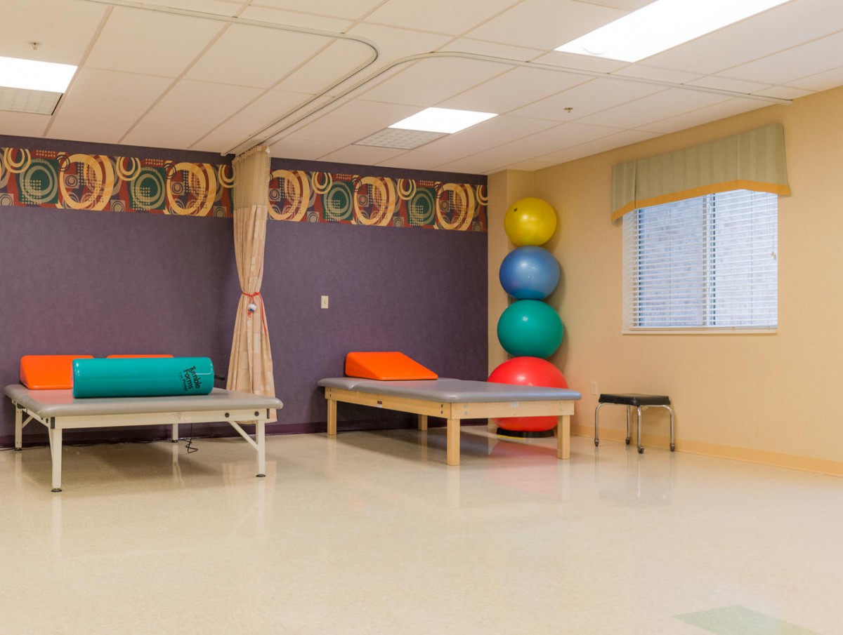 A therapy room equipped with treatment beds and stacked exercise balls.