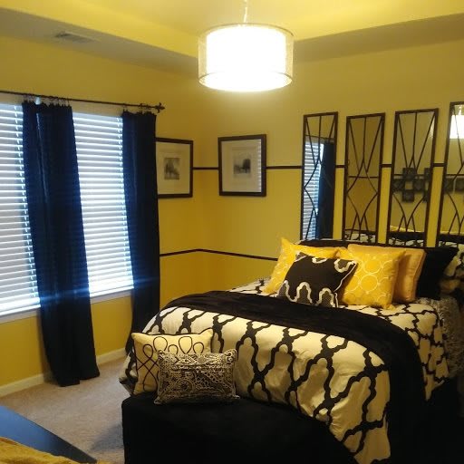 A modern bedroom with yellow walls and black and white decor.
