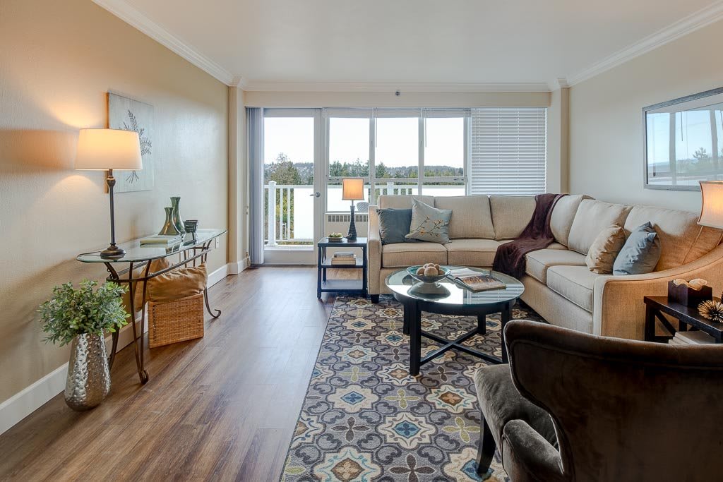 A cozy living room with a sectional sofa, coffee table, and a scenic window view.