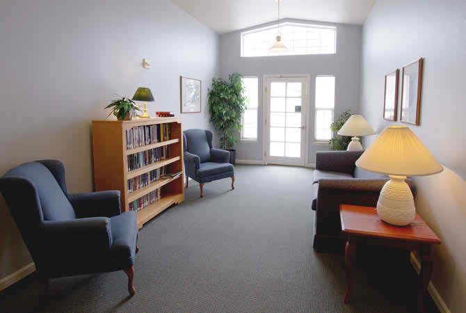 A cozy living room with comfortable seating, a bookshelf, and decorative plants creating a warm atmosphere.