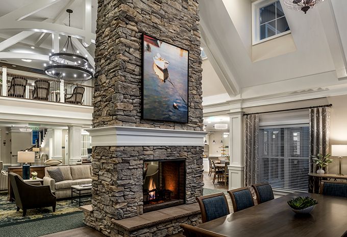 A luxurious open-concept living and dining area featuring a central stone fireplace with artwork above it.