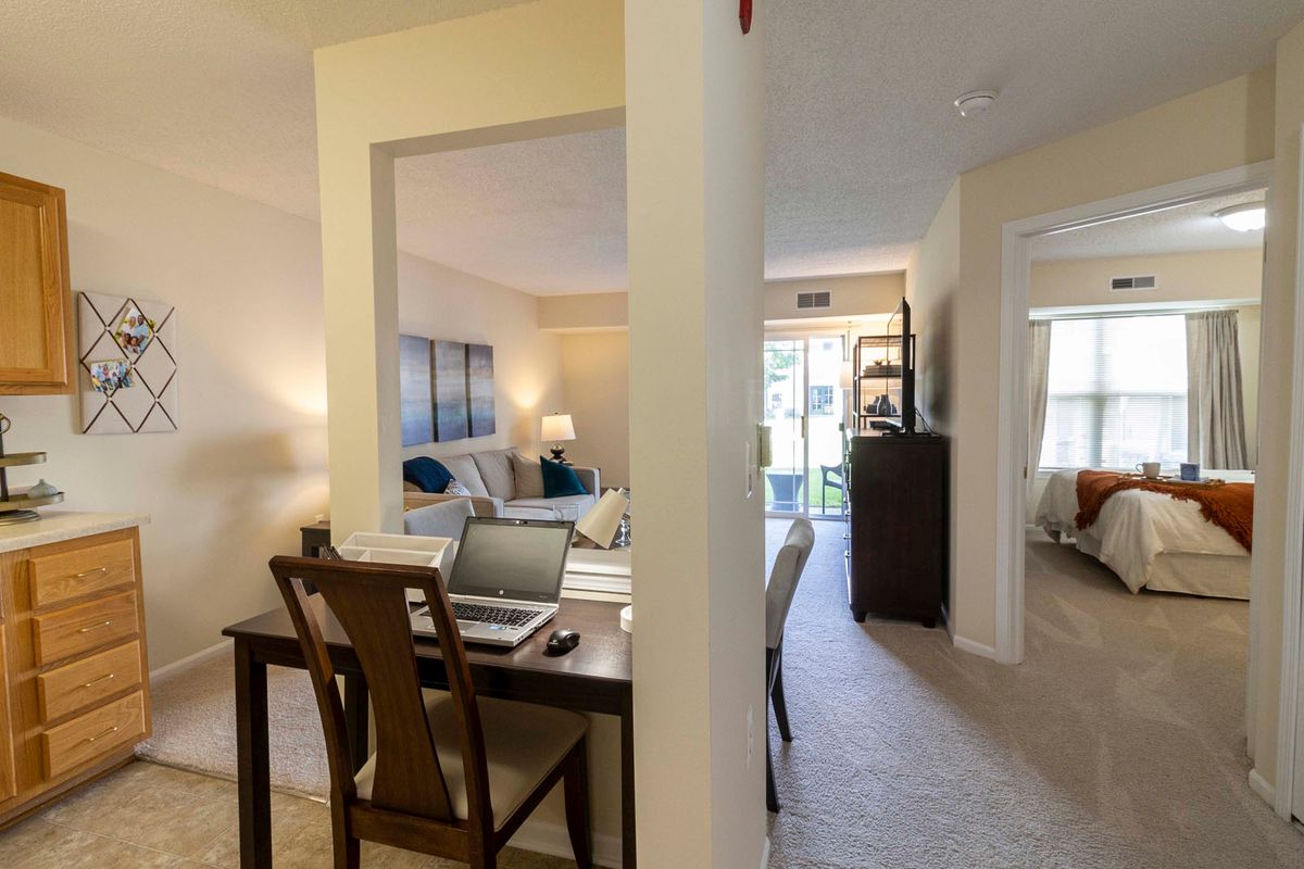 A cozy apartment interior featuring a living room with comfortable seating and an adjacent dining area set up as a workspace.