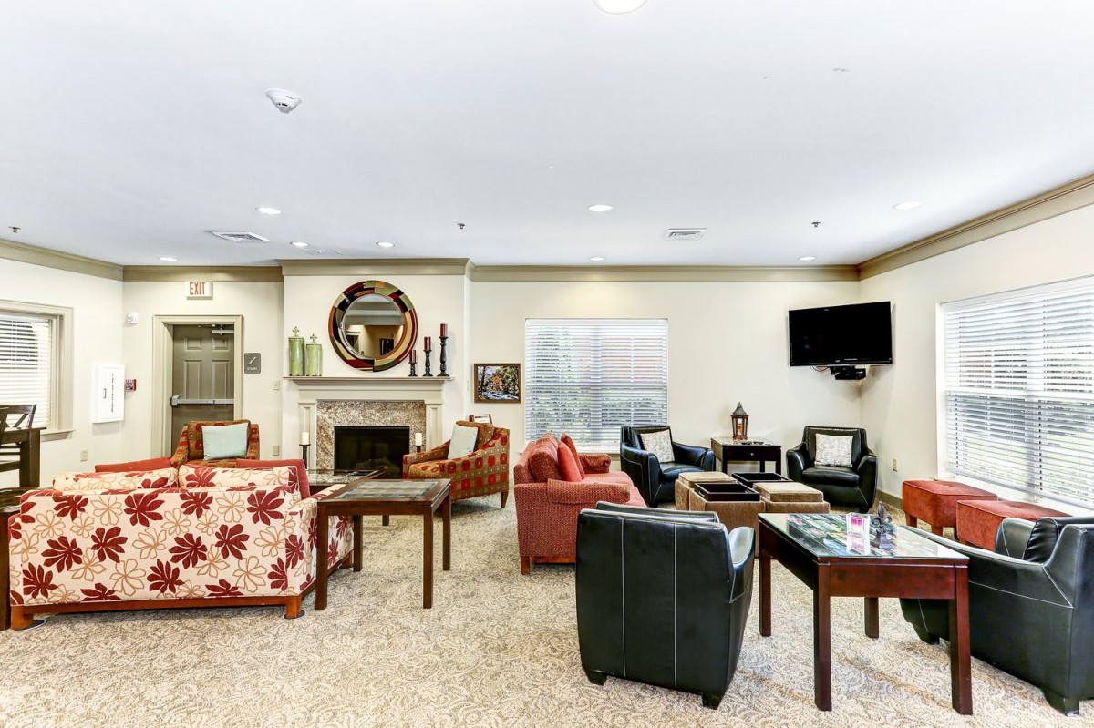 A cozy living room with various seating options, a fireplace, and a mounted television.