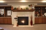 A cozy living room with a lit fireplace, adorned mantel, and decorative shelves.