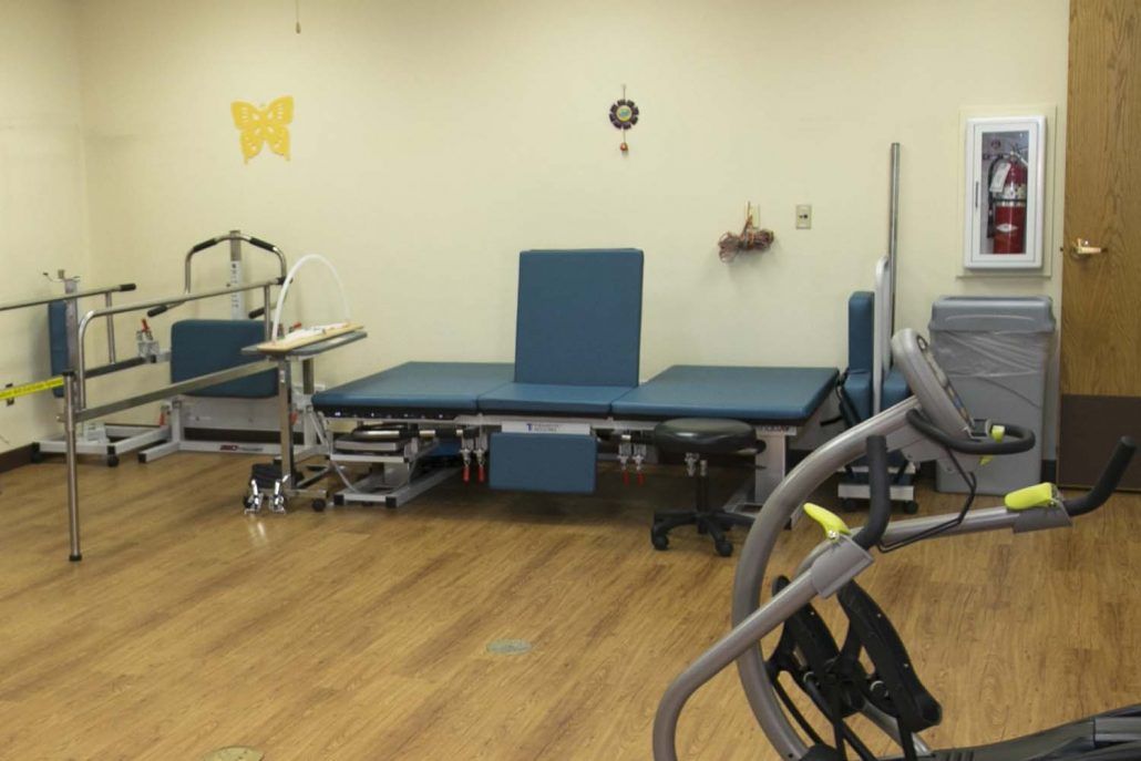 A physical therapy room equipped with a therapy table and various exercise equipment.