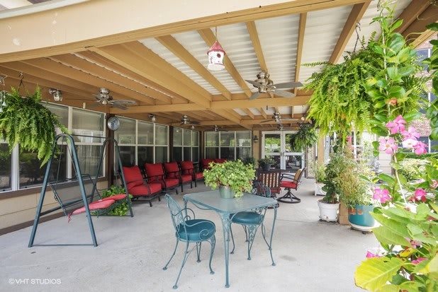 A cozy patio area with outdoor seating, surrounded by potted plants and covered by a pergola.