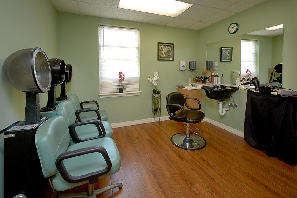 A cozy hair salon interior with chairs, a mirror, and salon equipment.