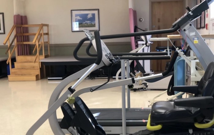 A gym with exercise equipment, including a treadmill, in an indoor setting.
