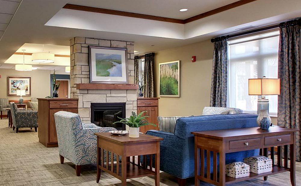 A cozy living room with a fireplace, couches, armchairs, and decorative artwork.