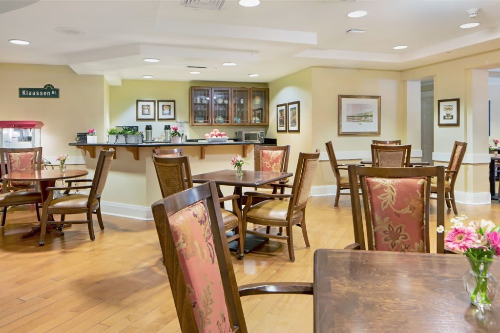 A cozy dining area with wooden tables and chairs, featuring elegant decor and wood flooring.