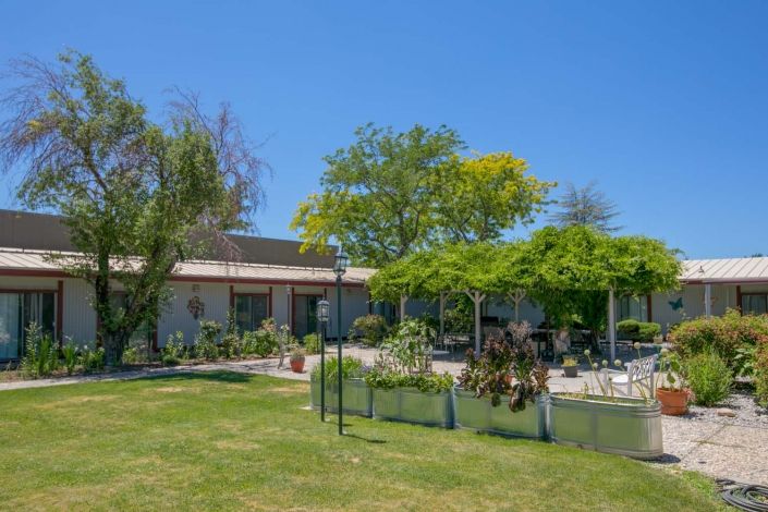 A sunny day view of a building surrounded by lush greenery and trees.