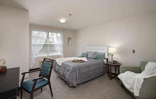 A cozy and well-lit bedroom featuring a comfortable bed, stylish chair, and charming decor.