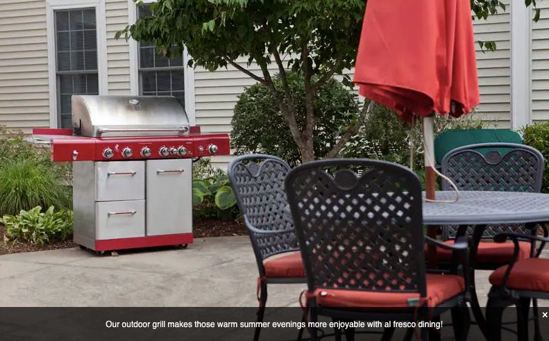 A cozy patio setup with a red grill and umbrella, perfect for summer evenings.