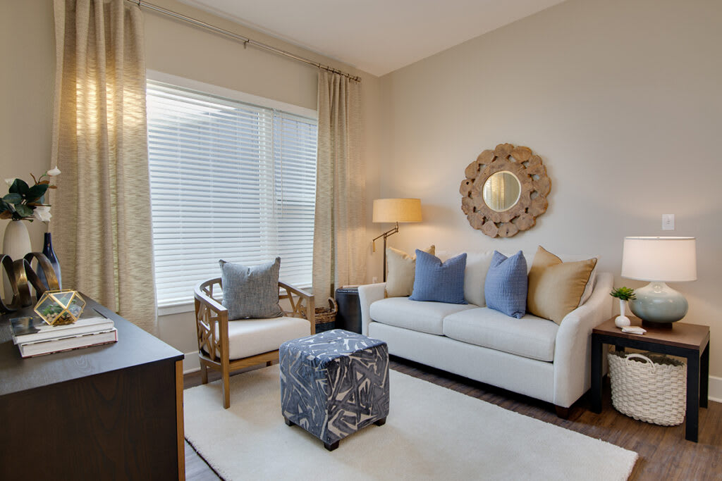 A cozy and modern living room with a sofa, armchair, decorative mirror, and floor lamp.