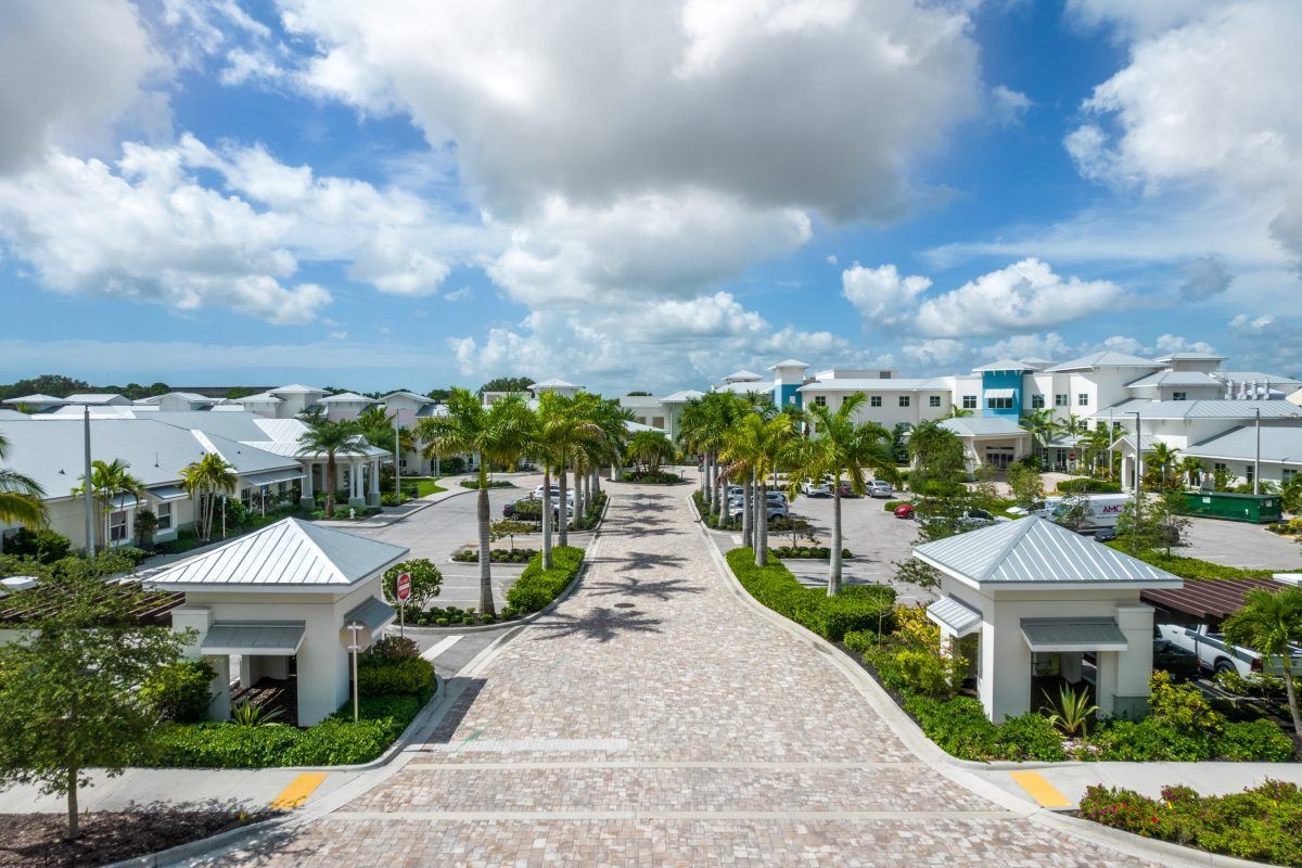 A luxurious tropical resort with palm-lined pathways under a partly cloudy sky.
