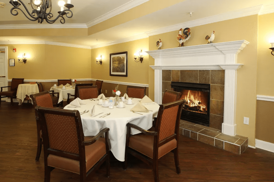 A cozy dining room with a fireplace, elegantly set table, and comfortable chairs.