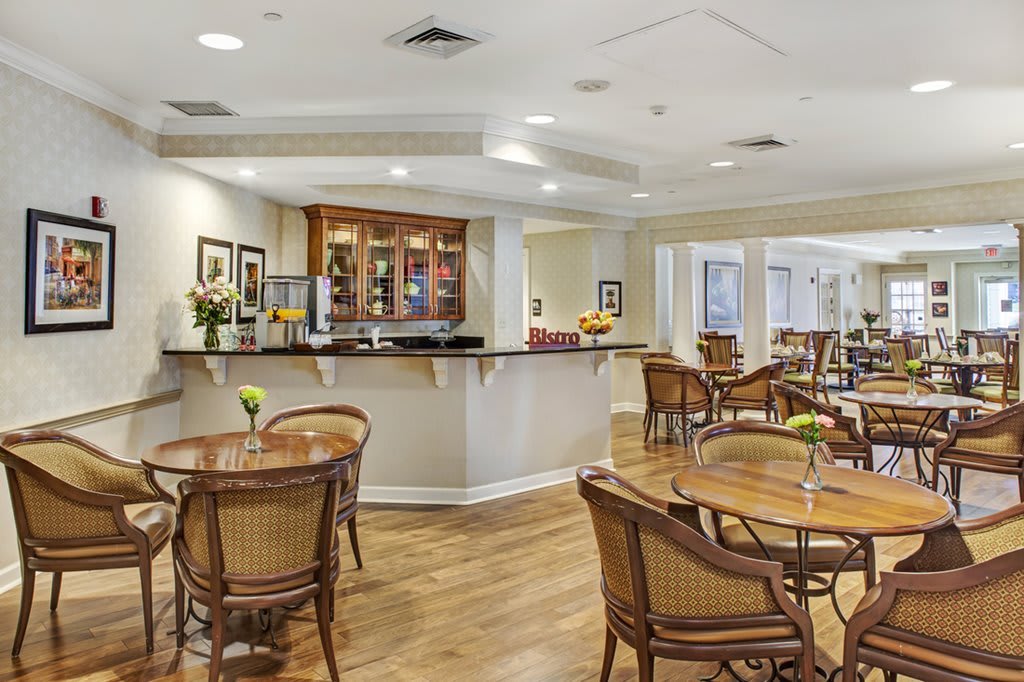 A cozy cafe interior with a bar counter, wooden tables, and chairs.
