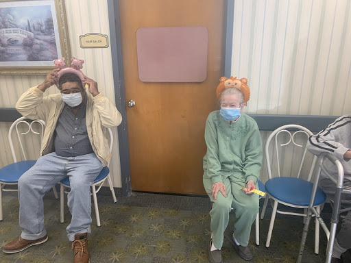Two individuals wearing masks and playful costumes sitting together indoors.