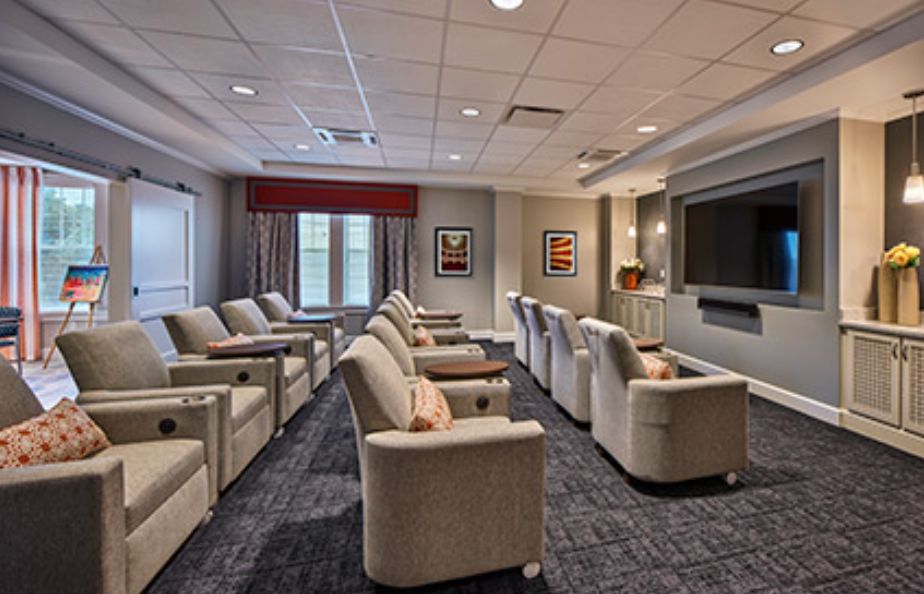 A modern home theater room with multiple recliner chairs facing a large projection screen.