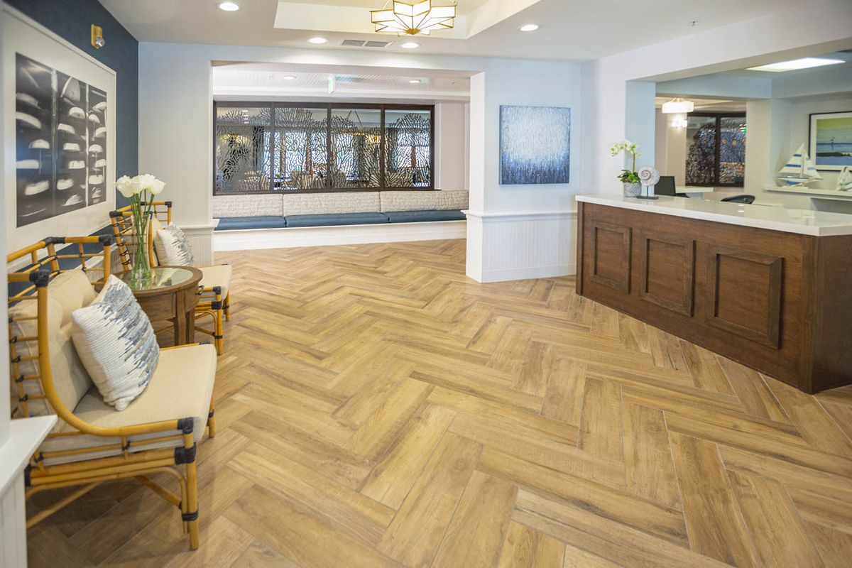 A modern lobby with wood flooring and a reception desk, featuring elegant interior design.