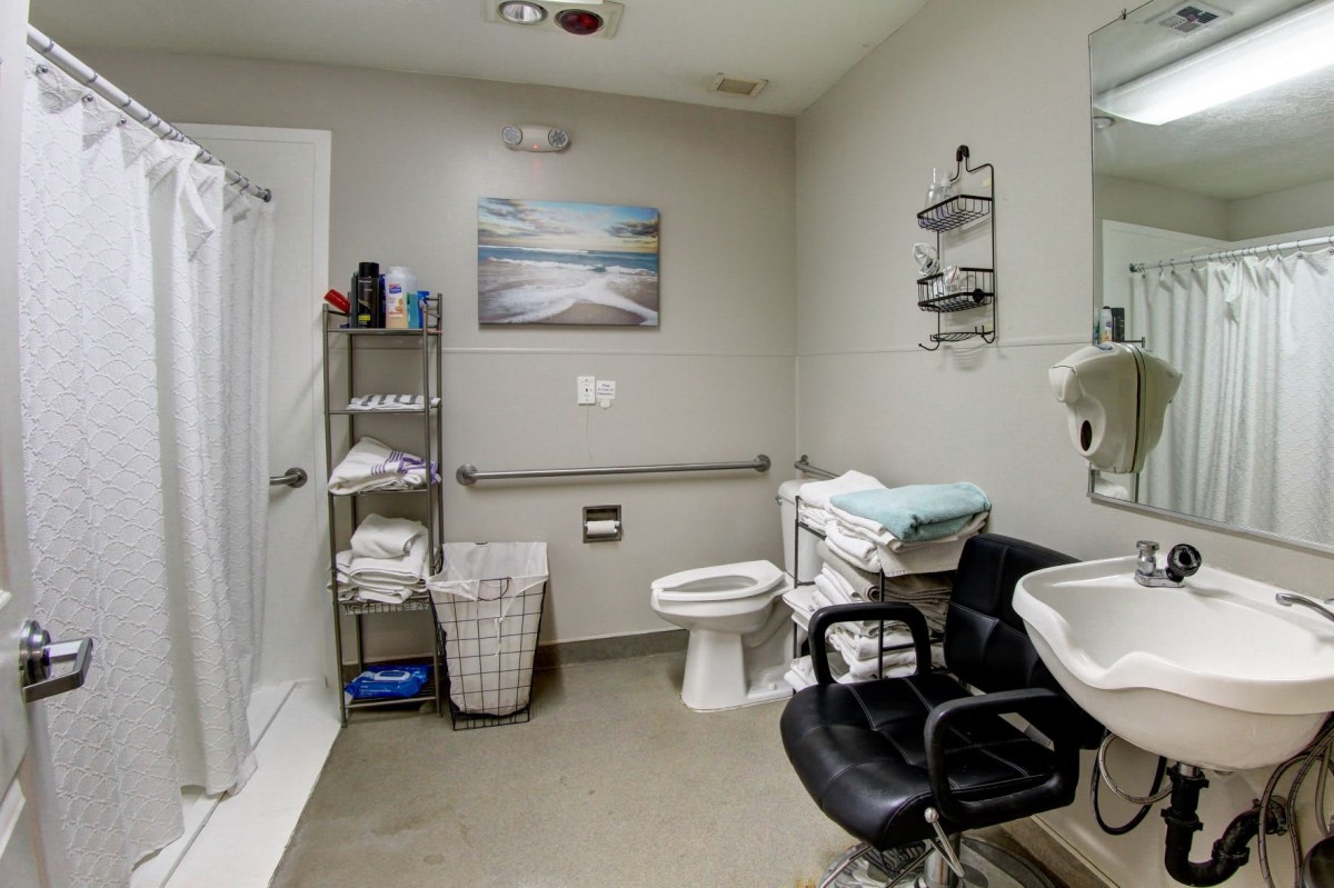 A modern bathroom equipped with a shower, sink, toilet, and storage shelves.