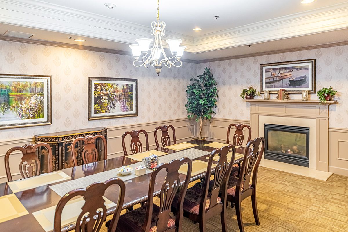 A traditional dining room with a long table, elegant chairs, and a chandelier.