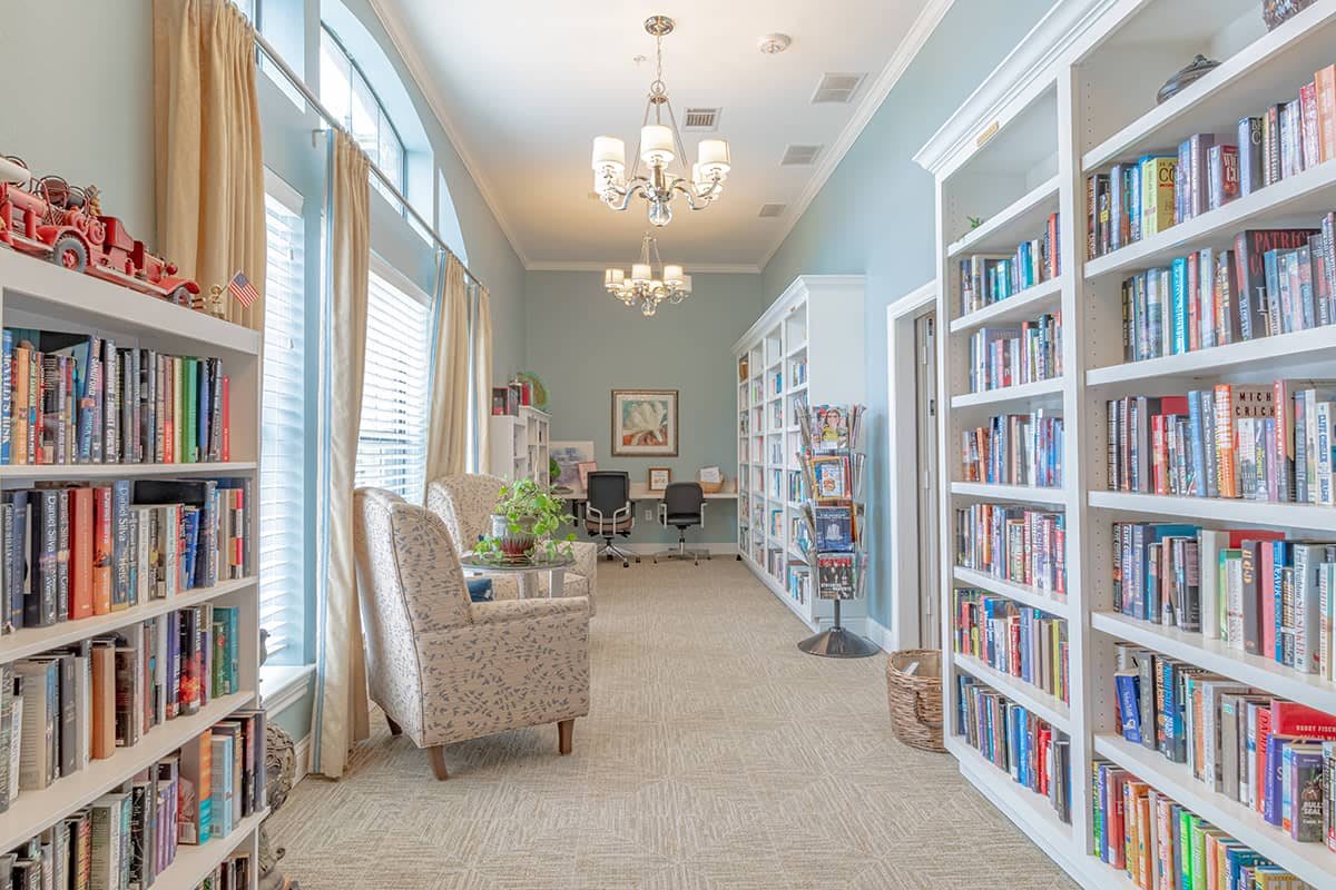 A cozy library room with bookshelves, comfortable chairs, and elegant lighting.