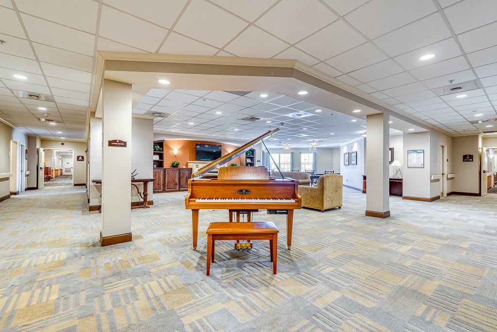A spacious lobby featuring a grand piano, with modern decor and bright lighting.