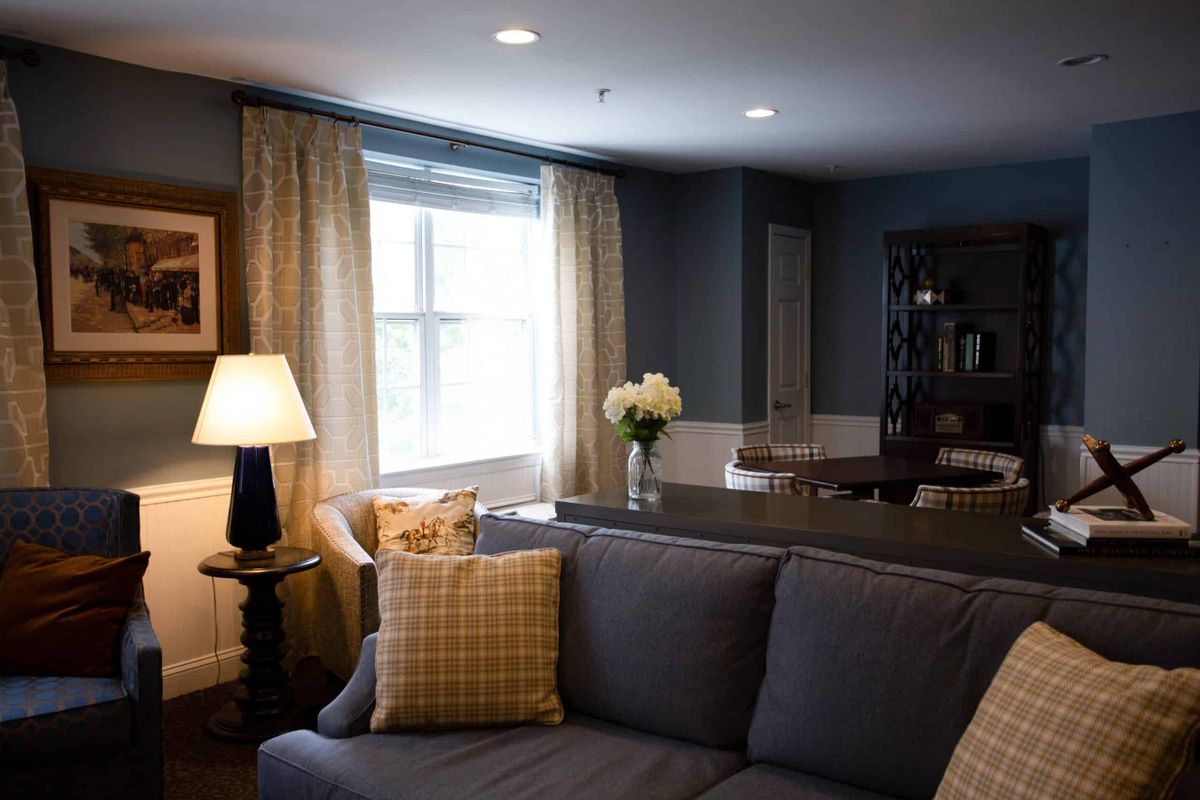 A cozy living room with a gray sofa, a lit lamp on a side table, and decorative pillows.