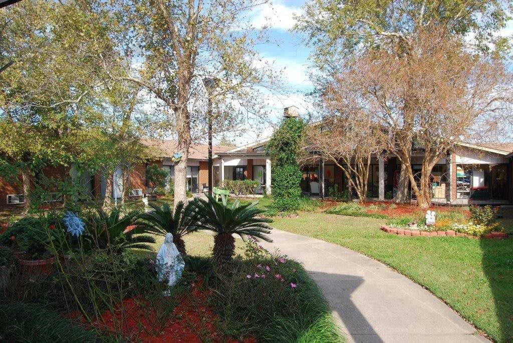 A scenic garden with a pathway leading to a building surrounded by trees and greenery.