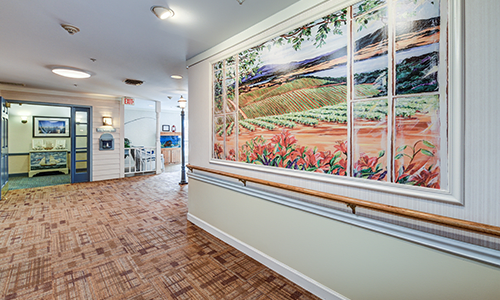 A well-lit hallway featuring a large landscape painting and wooden flooring.